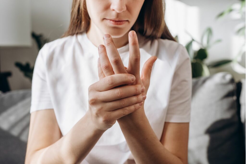 Foto de una mujer tocándose su mano, dolorida por artritis reumatoide