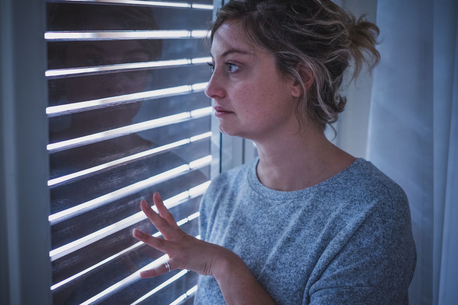 Mujer que tiene agorafobia mira detrás de su ventana